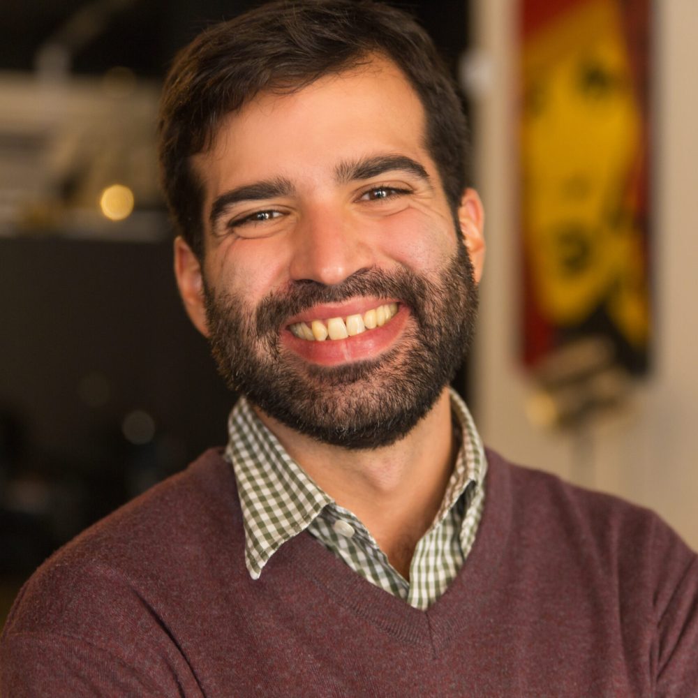 Closeup of happy joyful bearded guy posing indoors. Young man wearing casual, looking at camera and smiling. Male portrait concept